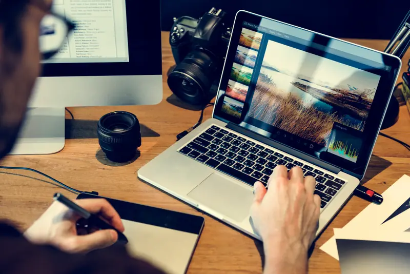 Designer editando imagens no notebook com mesa digitalizadora