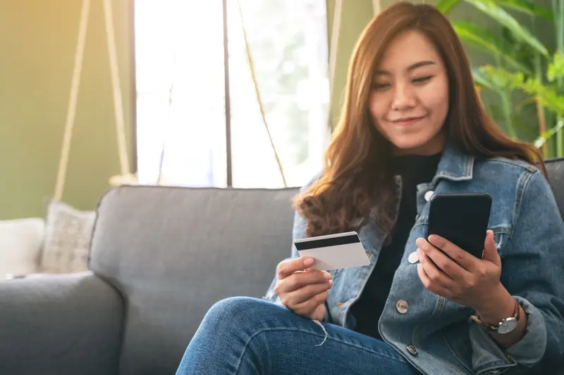 Mulher fazendo uma compra online pelo celular com cartão de crédito